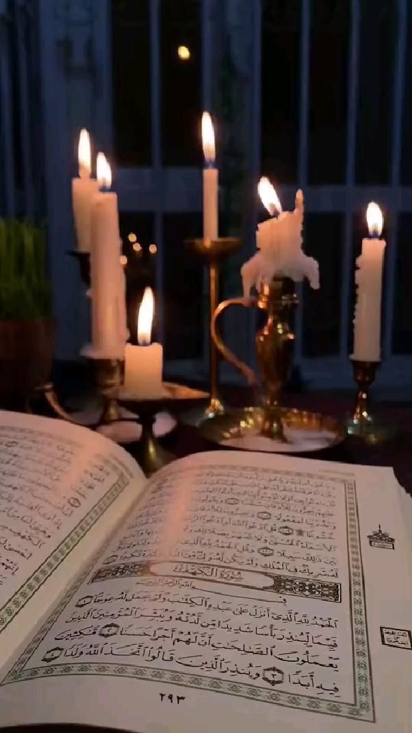 an open book sitting on top of a table next to candles