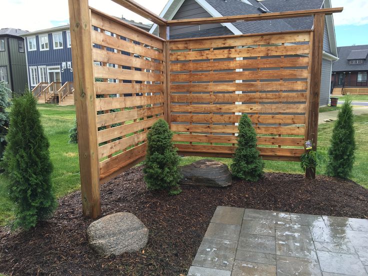 a wooden fence in the middle of a yard next to a stone walkway and trees