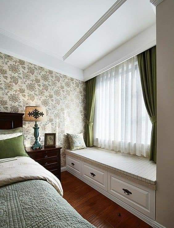 a bed room with a neatly made bed next to a window covered in green curtains