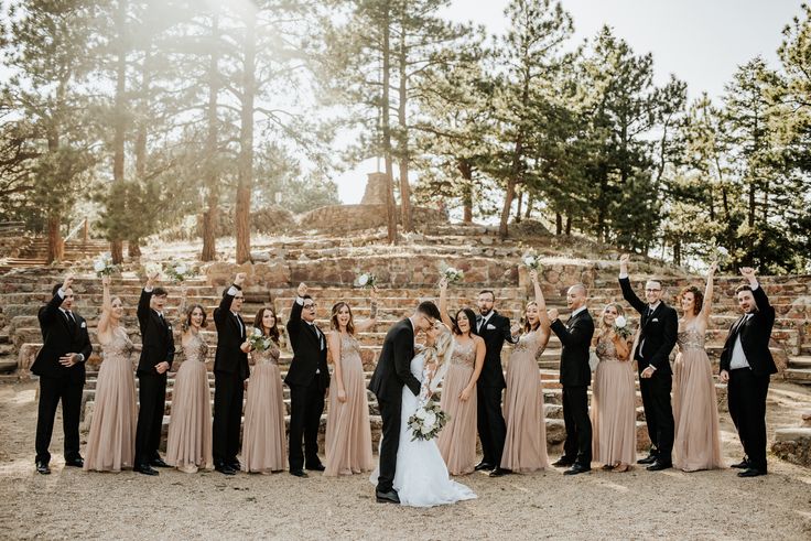 a large group of people standing next to each other in front of some rocks and trees