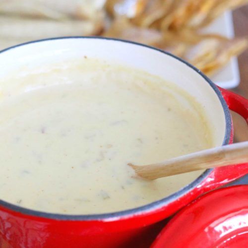 a red pot filled with soup sitting on top of a table next to crackers