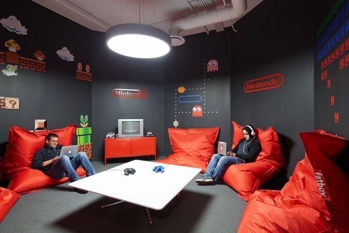 two people sitting on bean bag chairs in a room with video game themed wallpaper