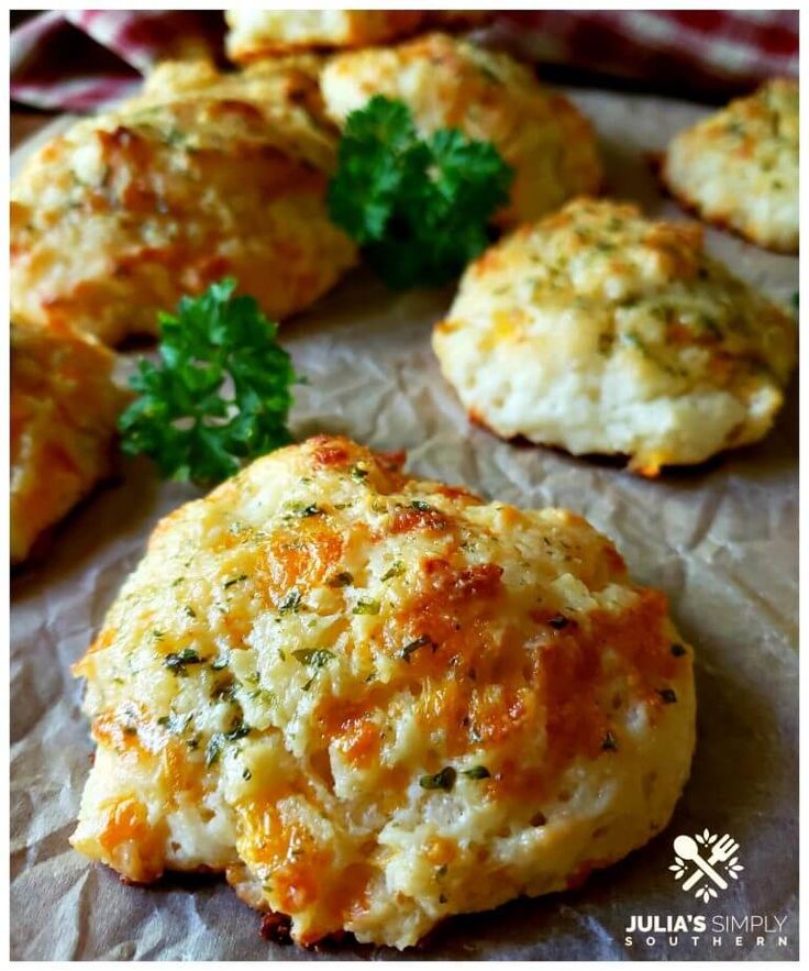 some biscuits with parsley on top of them sitting on wax paper next to each other