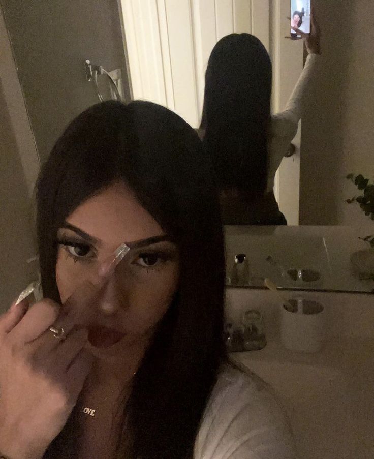 a woman is taking a selfie in the mirror with her finger on her nose