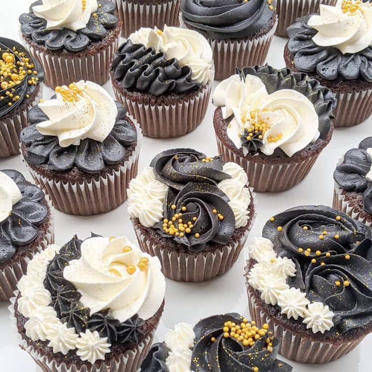 there are many cupcakes with white and black frosting