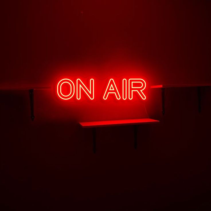 a red neon sign that says on air above a shelf in a dark room with no lighting