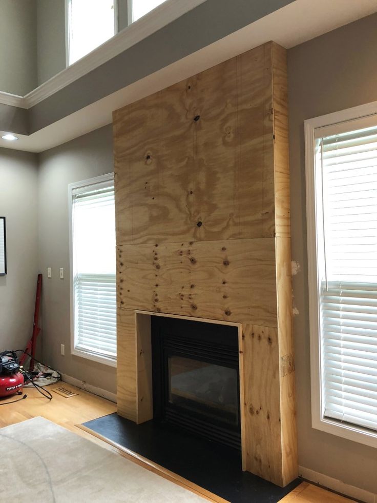 a living room with a fire place in the center and windows on both sides of it