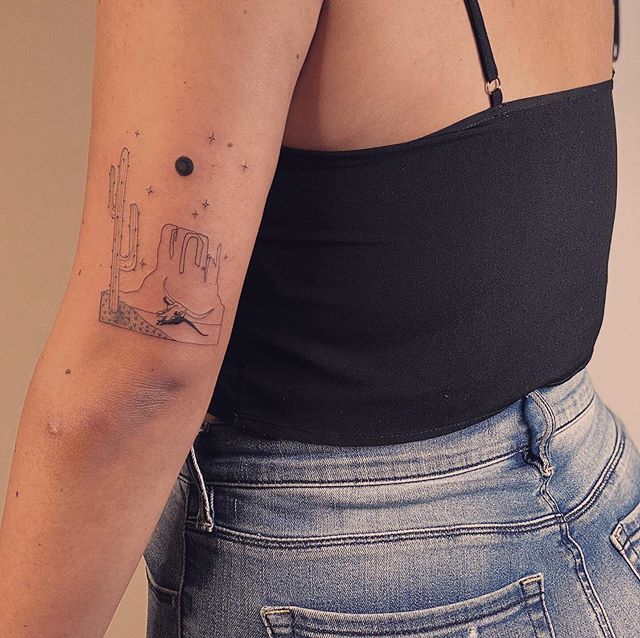 a woman with a small tattoo on her left arm and right arm behind her back