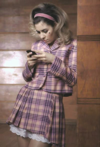 a woman is looking at her cellphone while wearing a plaid coat and tights