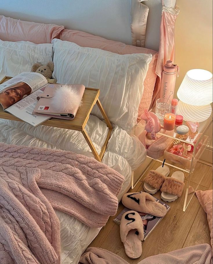 a bed with pink sheets and blankets on top of it next to a night stand