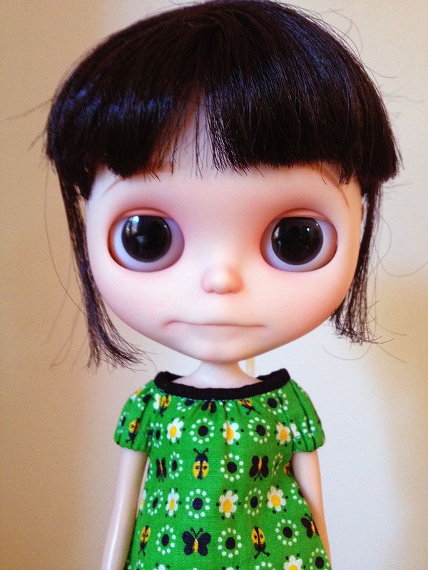 a close up of a doll wearing a green dress with flowers on it's chest