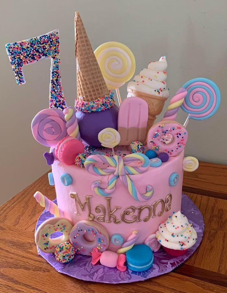 a pink birthday cake decorated with candy and candies, including an ice cream cone