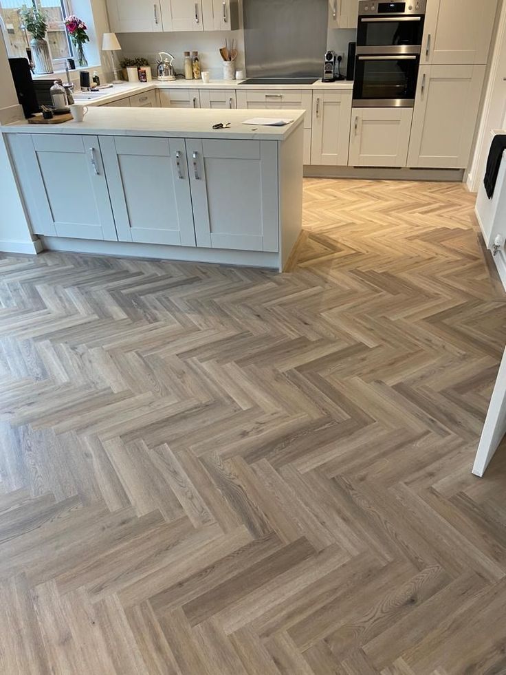 a kitchen with white cabinets and wood flooring