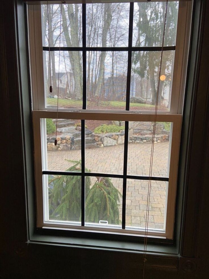 an open window with the view of a brick patio and trees in the back yard