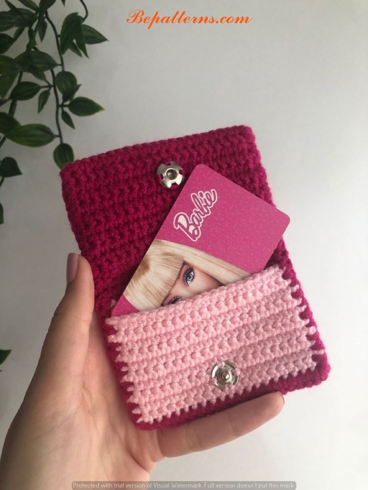 a hand holding a pink crocheted purse with a card holder attached to it