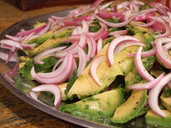 the salad has onions, avocado and onion on it in a bowl with a spoon