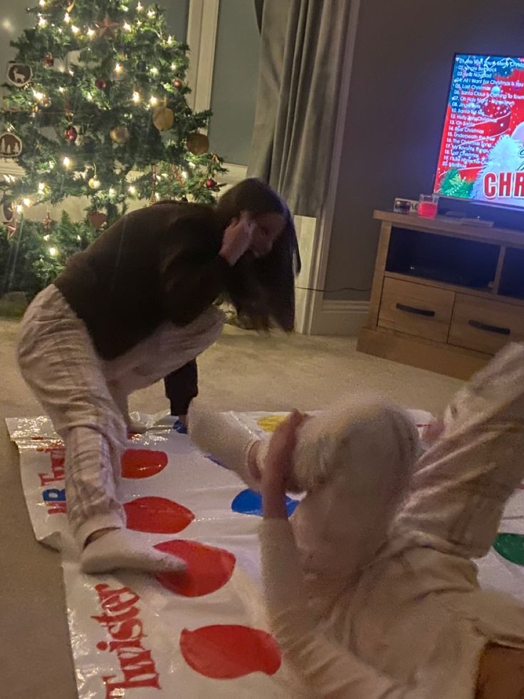 two children are playing with paper plates on the floor in front of a christmas tree