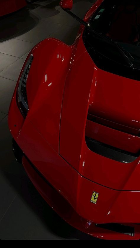 the front end of a red sports car in a showroom with its hood up