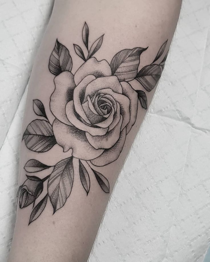 a black and white rose tattoo on the arm