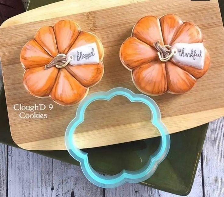 two pumpkin shaped cookie cutters sitting on top of a cutting board