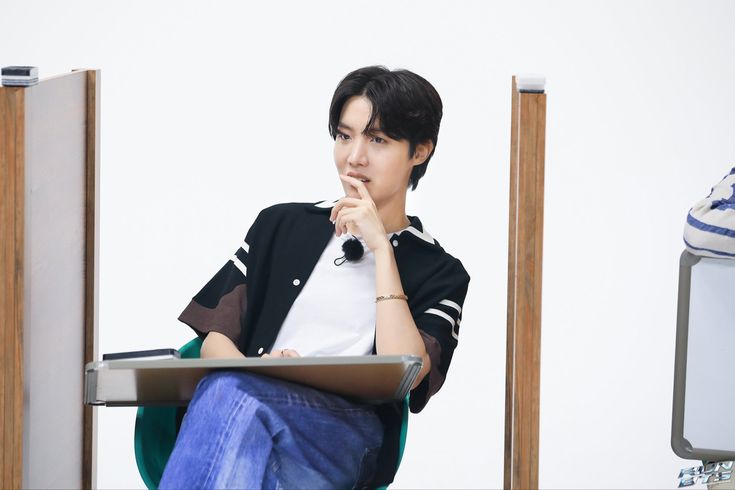 a young man sitting in front of a laptop computer on top of a green chair