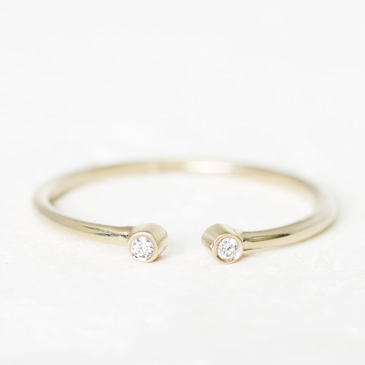 a gold ring with two small diamonds on the top and one smaller diamond in the middle