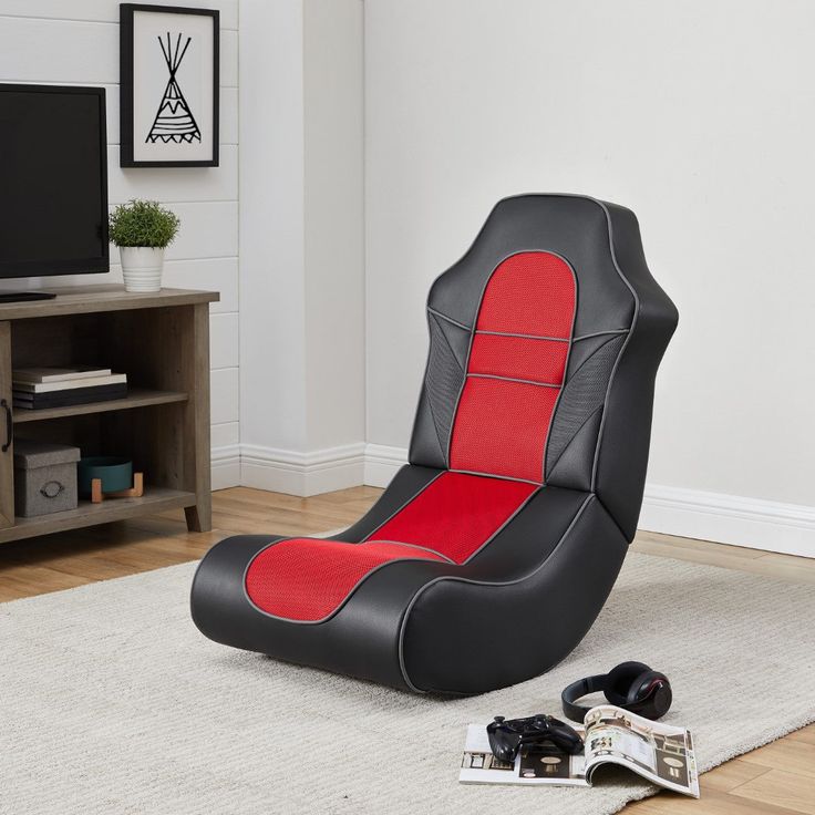 a black and red gaming chair sitting on top of a rug next to a tv