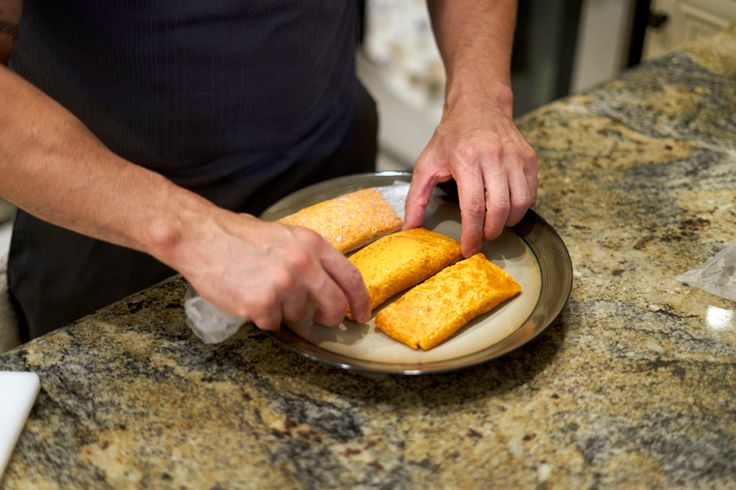 a man is cutting up some food on a plate in front of the kitchen counter