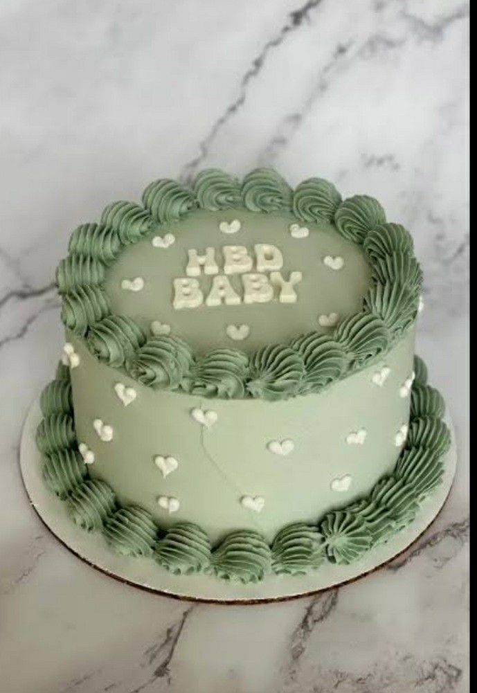 a green and white baby cake on a marble counter top with the words hbd baby written in frosting