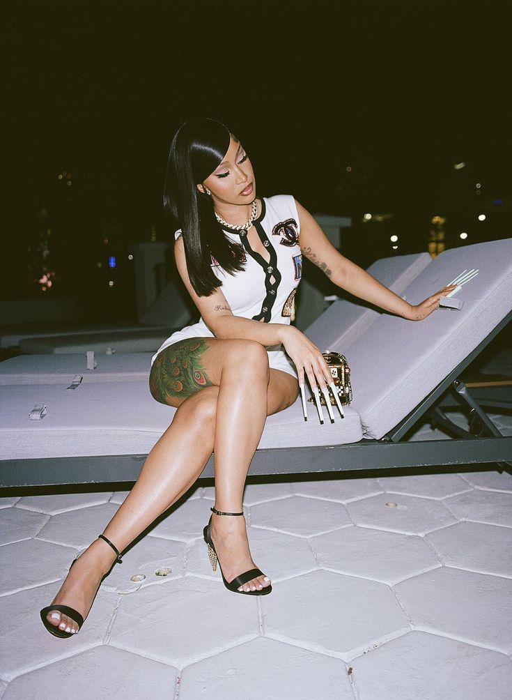 a woman sitting on top of a bed next to a white mattress and wearing heels