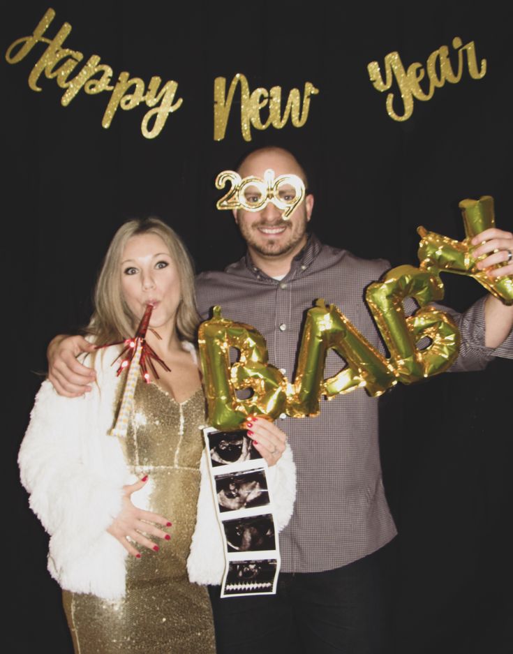 a man and woman posing for a photo in front of a happy new year sign