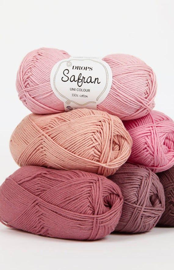 three skeins of yarn in pink, purple and beige colors on a white background