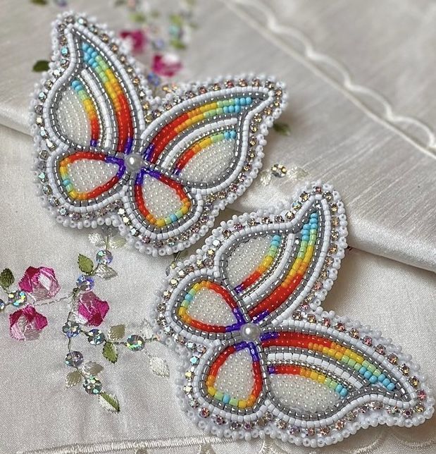 two colorful butterfly appliques sitting on top of a white satin material covered table cloth