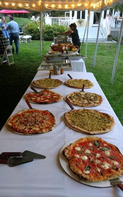 several pizzas are on the table ready to be served at an outdoor party or social gathering