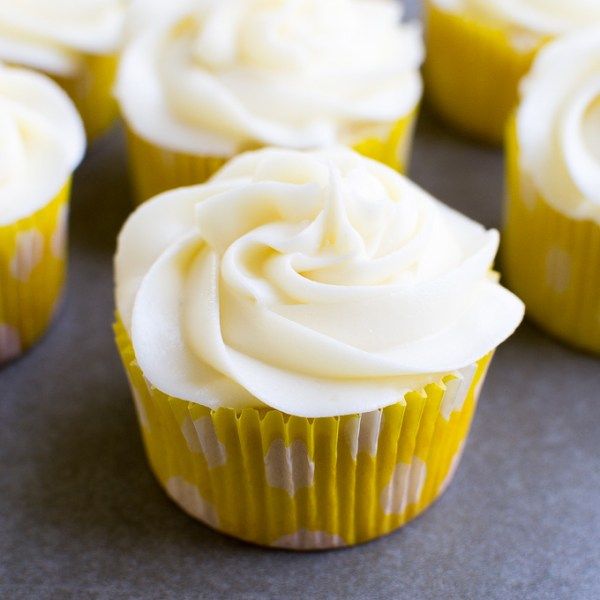 cupcakes with white frosting sitting on top of a gray countertop next to each other