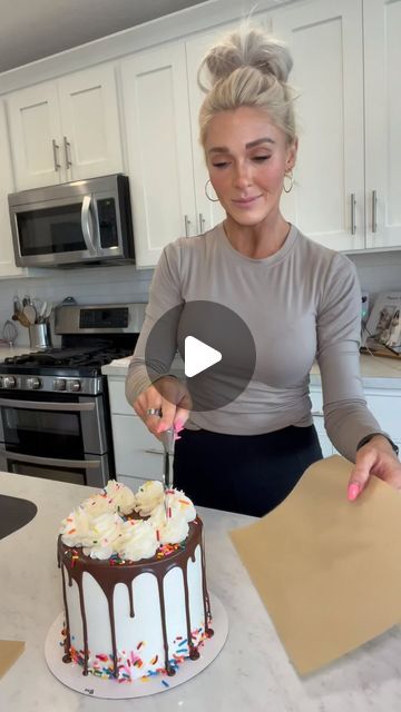 a woman is cutting into a cake with chocolate icing