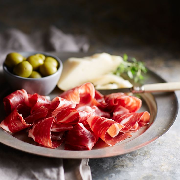 an assortment of meats and olives on a plate