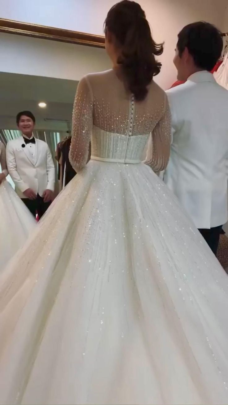 a woman in a wedding dress standing next to another man