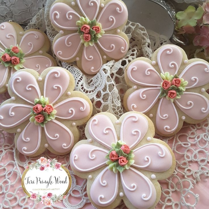 decorated cookies in the shape of flowers on a lace doily with pink and white icing