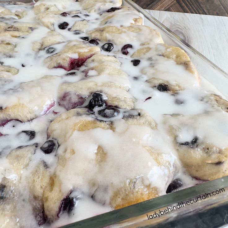 blueberry cobbler with icing and fresh berries on top, ready to be eaten