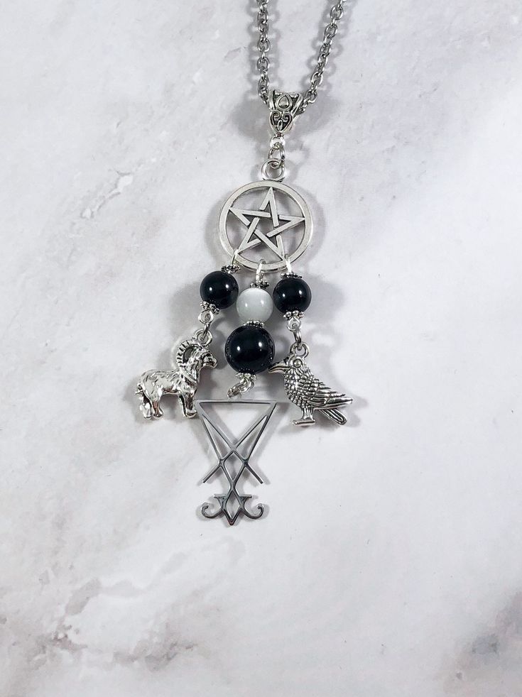 This beautiful chain necklace is the perfect way to express your affinity for Lucifer. Charms: Ram Sigil Crow 3 onyx beads and one selenite bead also make up the pendant. Your choice of top charm: Pentacle or Chandelier Available in a variety of lengths. Secured with a lobster clasp. Chain is stainless steel. Charms are zinc alloy. All materials are lead and nickel free. Comes in a jewelry box so it's ready to be given as a gift. Have a idea for a custom order? I'd love to hear it! Just click th Spiritual Silver Charm Necklaces With Gemstone Beads, Spiritual Black Dangle Necklaces, Spiritual Black Necklaces With Charms, Slavic Goddess, Greek Mythology Jewelry, Mythology Jewelry, Sparkly Accessories, Grunge Jewelry, Garnet Bracelet