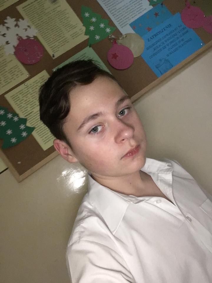 a young man sitting in front of a bulletin board