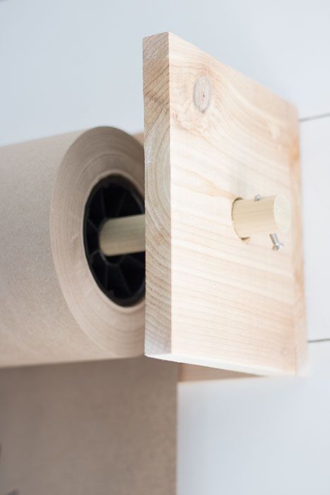 a roll of toilet paper sitting on top of a wooden holder next to a wall