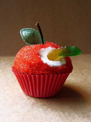 a red cupcake with a piece of fruit on it's side sitting on a table