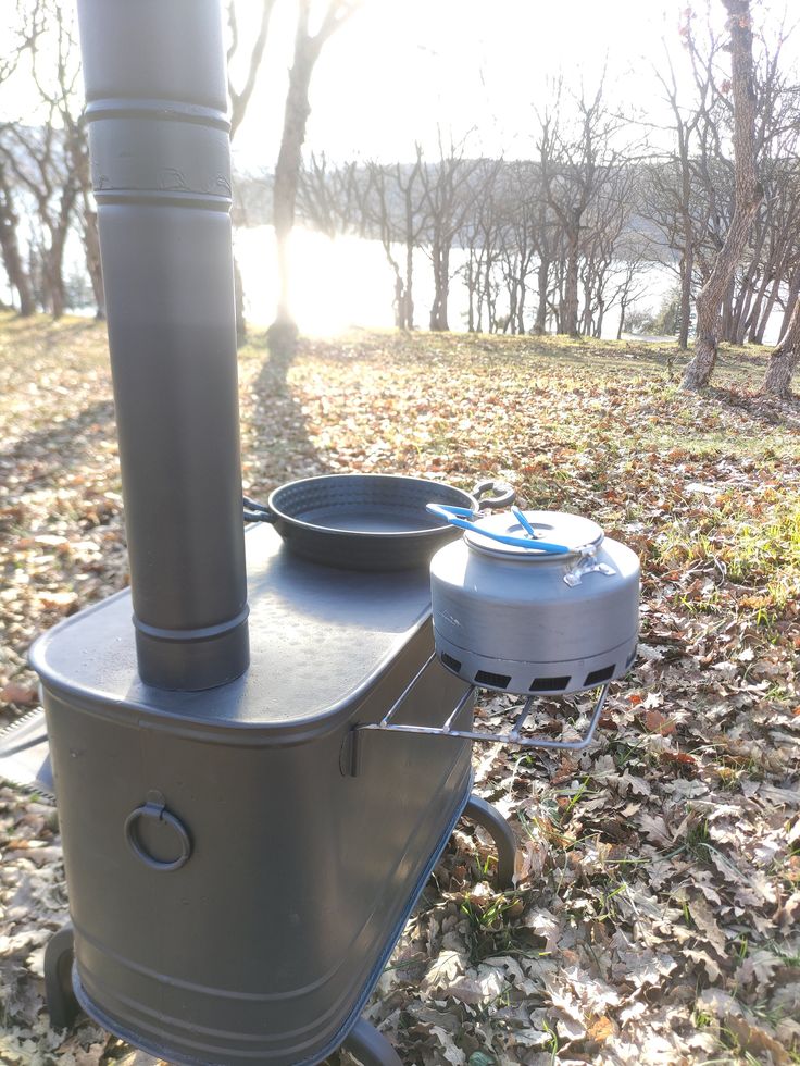 an outdoor stove sitting on top of leaves covered ground