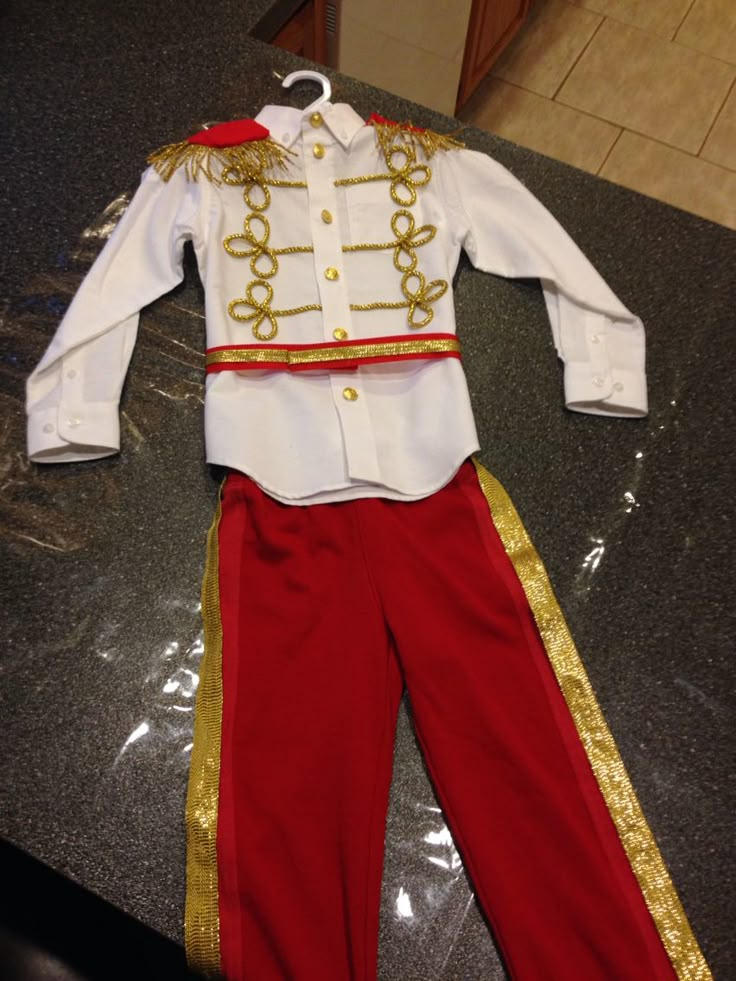 a white shirt and red pants with gold trimmings on the bottom, sitting on top of a counter