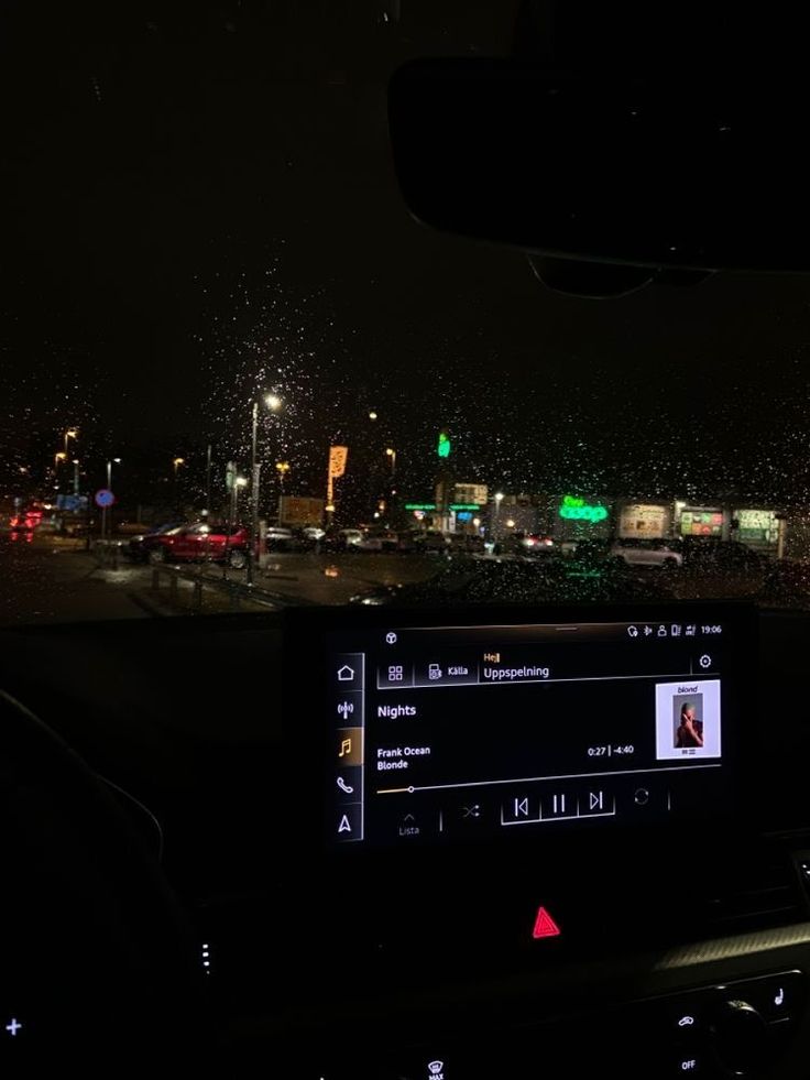 the dashboard of a car at night with fireworks in the air and buildings behind it