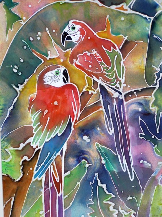 two colorful parrots sitting on top of a tree branch in front of some leaves