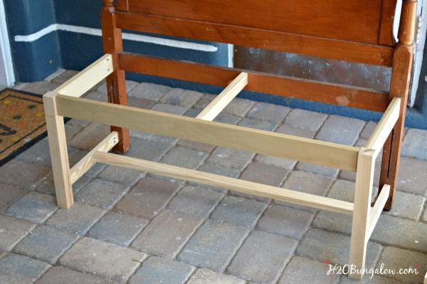 a wooden bench sitting on top of a brick floor next to a blue wall and door