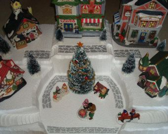 there are many christmas decorations on the table together in front of small houses and trees